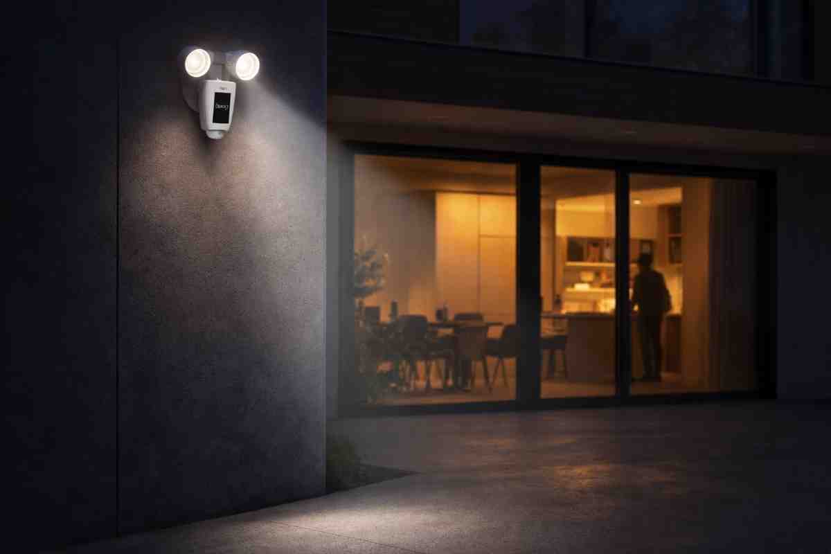Ring Floodlight Cam Wired Plus mounted on a modern home exterior at night, illuminating the driveway